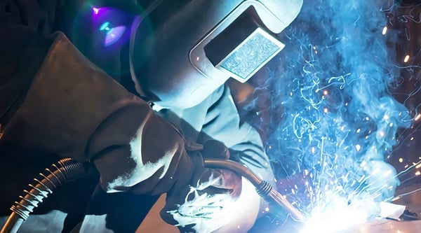 Image of welder with gasses coming off from the weld work - a key consideration for hot work permits in construction safety.